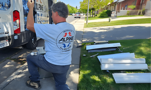 HVAC technician from Alpine Heating & Air Conditioning working near a service van during an installation